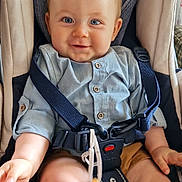 Elio participe au concours pour gagner de l'argent avec cette photo : baby, child, car_seat, blue_eyes, smiling, shirt, shorts, safety_harness, indoor, seat_belt, person, infant, cute, happy, hands, legs, fabric, buttons, closeup, comfort