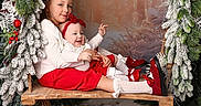 Lou a rejoint le concours — aidez-le/la à gagner de superbes lots ! baby, boots, child, christmas, cozy, cute, decorations, festive, headband, holiday, indoor, lantern, pine_garland, portrait, red_clothing, smiling, snow, swing, white_clothing, winter