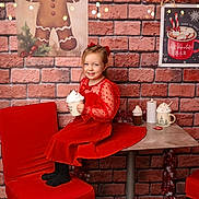 Théa participe au concours pour gagner de l'argent avec cette photo : child, girl, red_dress, holiday, christmas, mug, whipped_cream, table, chair, brick_wall, decorations, lights, gingerbread_man, hot_chocolate, candle, smile, indoor, festive, happy, portrait