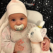 Sana participe au concours pour gagner de l'argent avec cette photo : adorable, baby, babywear, blanket, cat_toy, child, clothing, cushion, cute, eyes, face, hand, hat, indoor, infant, lying_down, pacifier, soft_toy, stars_pattern, stuffed_animal