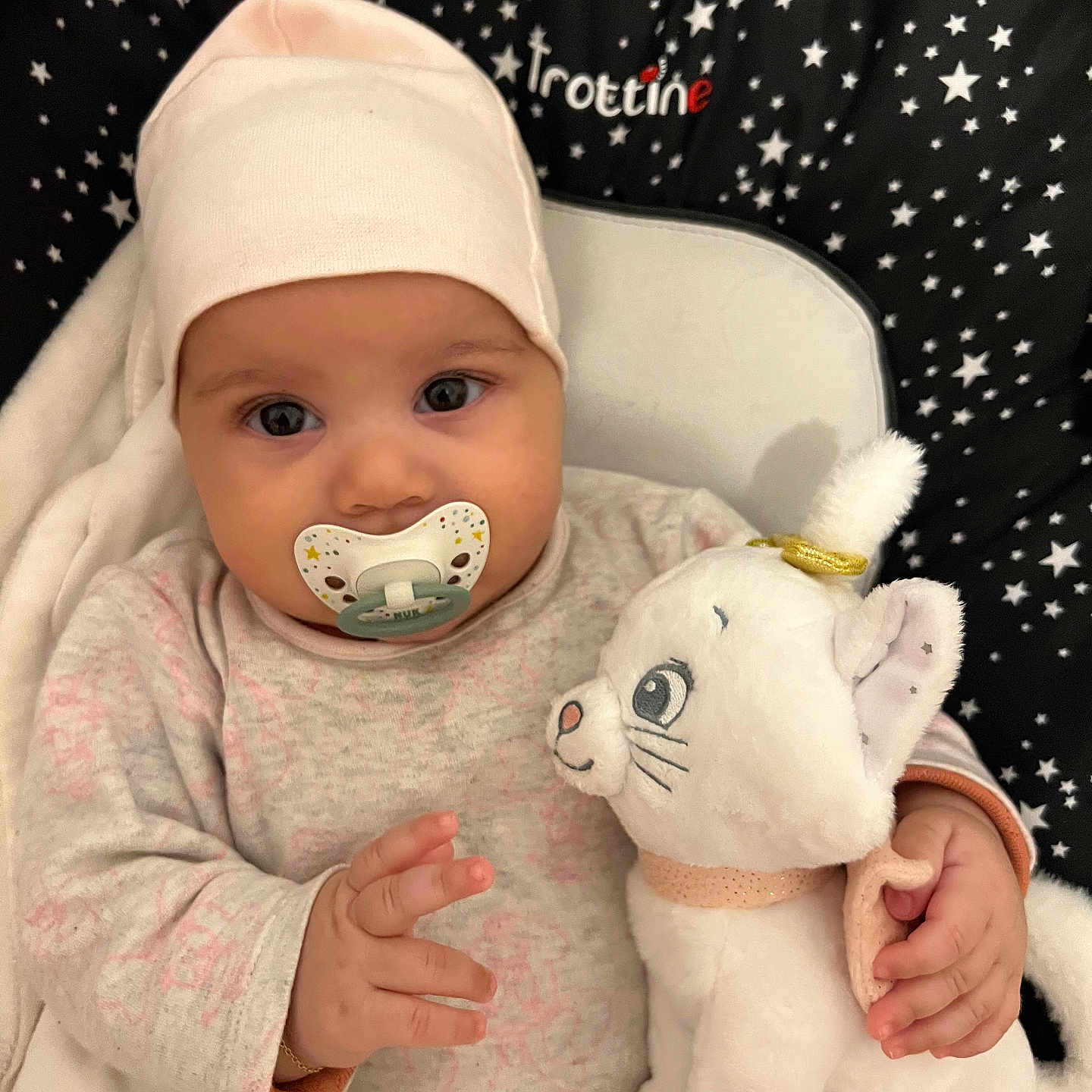 Sana participe au concours pour gagner de l'argent avec cette photo : adorable, baby, babywear, blanket, cat_toy, child, clothing, cushion, cute, eyes, face, hand, hat, indoor, infant, lying_down, pacifier, soft_toy, stars_pattern, stuffed_animal