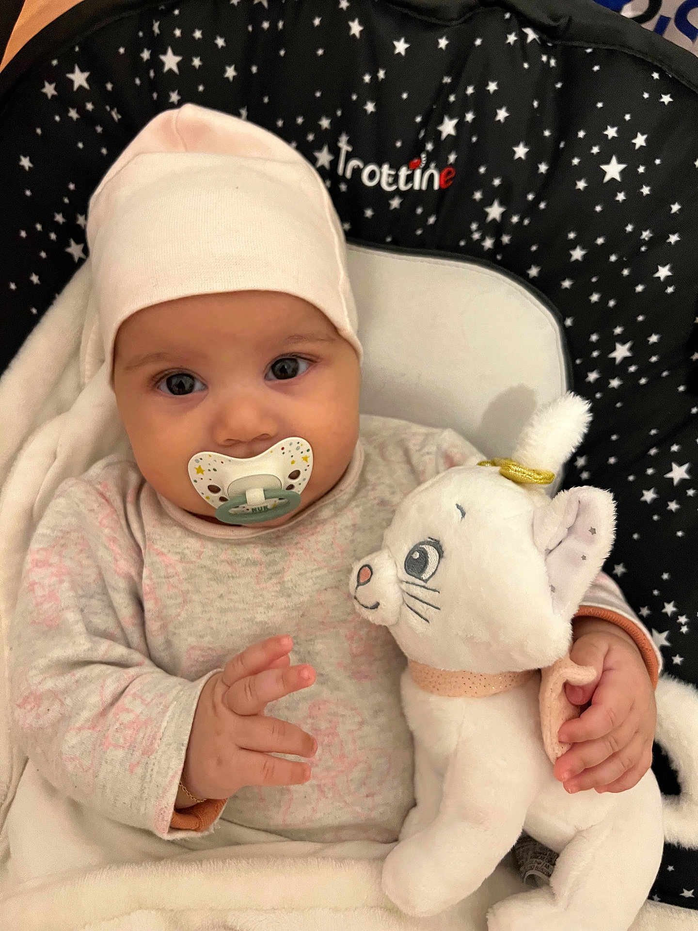 Sana participe au concours pour gagner de l'argent avec cette photo : adorable, baby, babywear, blanket, cat_toy, child, clothing, cushion, cute, eyes, face, hand, hat, indoor, infant, lying_down, pacifier, soft_toy, stars_pattern, stuffed_animal