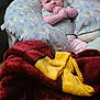baby, infant, blanket, couch, pillow, elephant_pattern, child, indoors, cozy, hand, face, person, clothing, sitting, soft, comfort, cute, home, relaxation, pink_pants