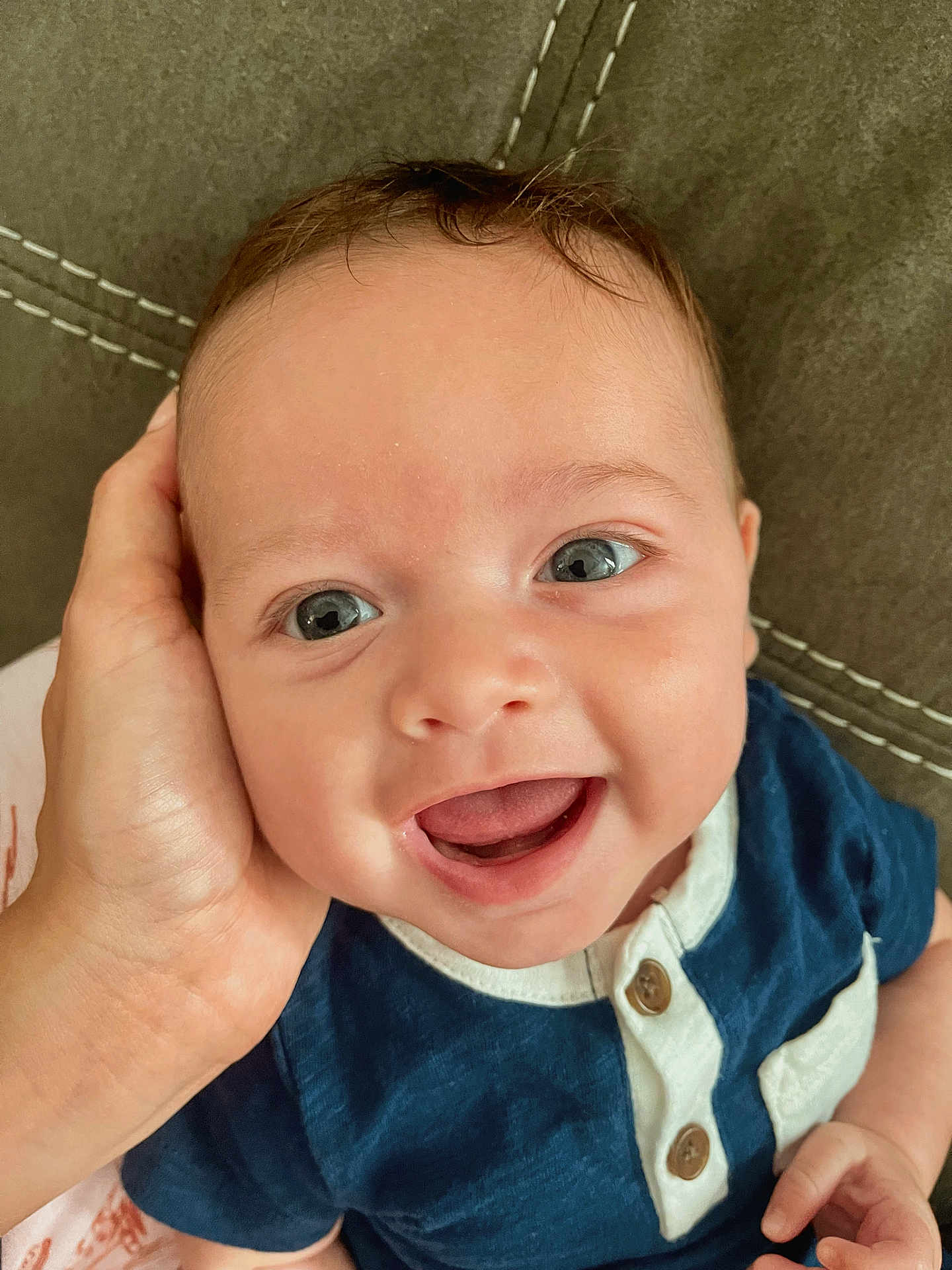Luca James is registered to the contest to win money with this photo: baby, smiling, face, hand, clothing, blue_shirt, infant, portrait, cute, happy, skin, eyes, mouth, person, closeup, child, seated, fabric, stitching, casual