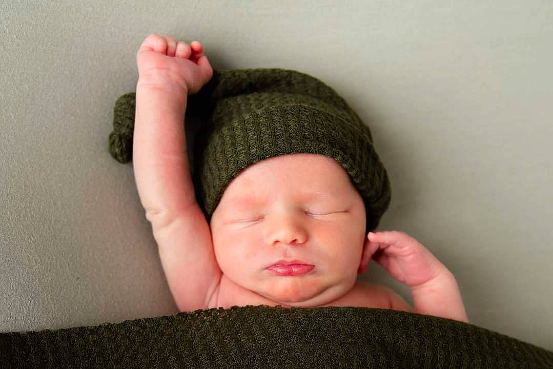 Emmitt is registered to the contest to win money with this photo: arm, baby, baby_sleeping, baby_toddler_clothing, cap, cheek, comfort, face, finger, gesture, head, headgear, headwear, human_body, knit_cap, linens, neck, person, sleeve, textile