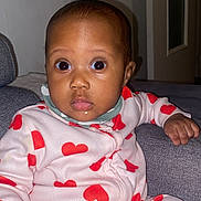 Jessica a rejoint le concours — aidez-le/la à gagner de superbes lots ! baby, infant, child, onesie, heart_pattern, pajamas, couch, living_room, face, wide_eyes, surprised_expression, sitting, hand, flash_photography, indoor, door, pillow, skin_tone, portrait, clothing