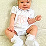 Wrenley is registered to the contest to win money with this photo: baby, child, infant, girl, smiling, headband, pink_bow, white_clothing, bracelet, socks, couch, indoor, portrait, cute, happy, seated, person, cozy, light_background, comfortable