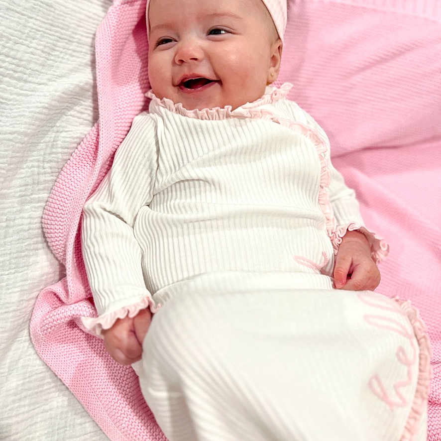 Wrenley is registered to the contest to win money with this photo: baby, infant, smiling, pink_bow, blanket, white_outfit, headband, lying_down, happy, portrait, child, cute, soft_texture, indoors, cozy, social_media, story, screen, mobile_interface, closeup
