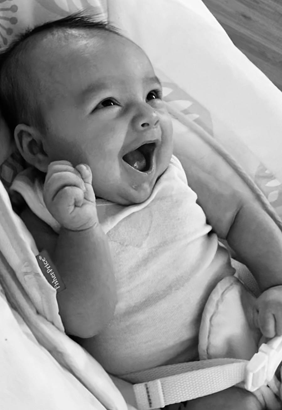 Lennon is registered to the contest to win money with this photo: arm, baby, black, cheek, chin, comfort, eye, gesture, hand, happy, human_body, iris, lip, mouth, nose, person, photograph, product, skin, smile