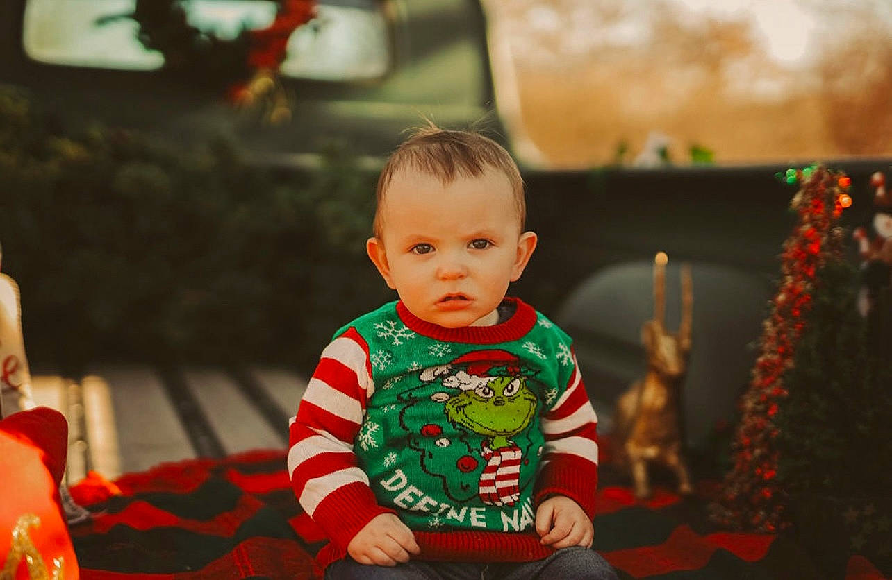 Brooks is registered to the contest to win money with this photo: baby, baby_toddler_clothing, chair, cheek, child, christmas, christmas_eve, event, facial_expression, fun, happy, holiday, leisure, orange, party, person, room, sitting, sleeve, toddler