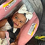 baby, child, smiling, headband, bow, car_seat, safety_harness, pink, gray, pacifier, hand, clothing, cute, infant, seat, happy, person, indoor, closeup, transportation