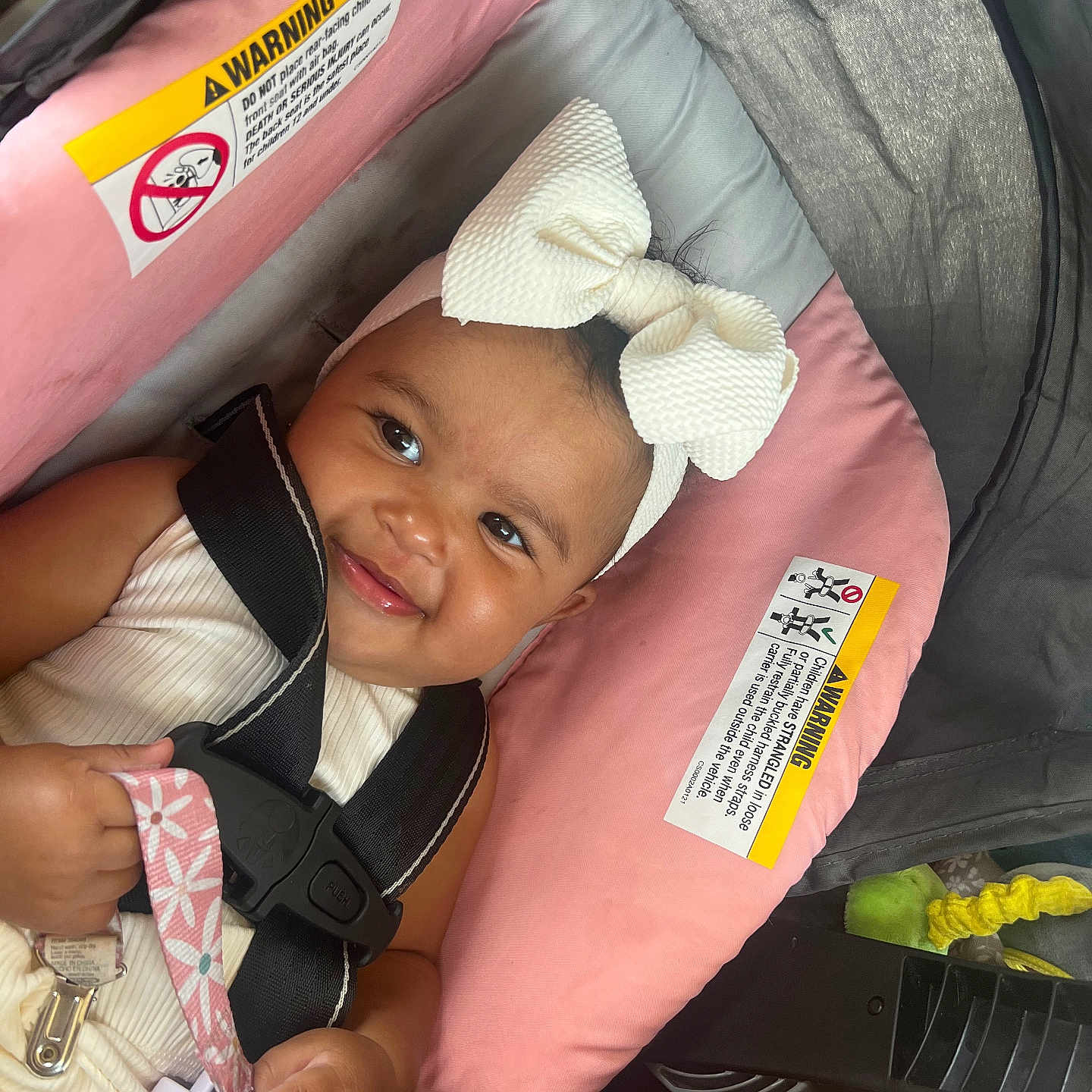 Ava is registered to the contest to win money with this photo: baby, bow, car_seat, child, closeup, clothing, cute, gray, hand, happy, headband, indoor, infant, pacifier, person, pink, safety_harness, seat, smiling, transportation