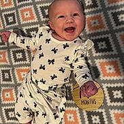 Serena joined the competition — help win amazing prizes! baby, smiling, infant, patterned_blanket, white_clothing, black_bows, wooden_sign, months, happy, lying_down, portrait, child, cute, cheerful, indoor, person, small_hands, small_feet, face, expression