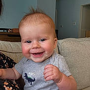 Elijah is registered to the contest to win money with this photo: baby, smiling, child, indoor, couch, clothing, dinosaur_graphic, grey_shirt, happy, portrait, toddler, furniture, home, person, cute, infant, sitting, hand, face, hair