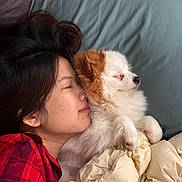 Bbingo is registered to the contest to win money with this photo: person, dog, bed, blanket, pillow, sleeping, snuggling, plaid_shirt, indoor, cozy, resting, fluffy_dog, close_up, peaceful, comfort, human_animal_bond, casual, relaxation, warmth, nap