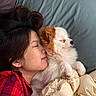 person, dog, bed, blanket, pillow, sleeping, snuggling, plaid_shirt, indoor, cozy, resting, fluffy_dog, close_up, peaceful, comfort, human_animal_bond, casual, relaxation, warmth, nap