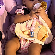 Blessyn is registered to the contest to win money with this photo: baby, child, car_seat, pink, bow, pacifier, soft_toy, baby_clothes, footwear, infant, cute, seated, indoors, sunlight, adorable, ribbons, clothing, person, young_child, baby_accessories