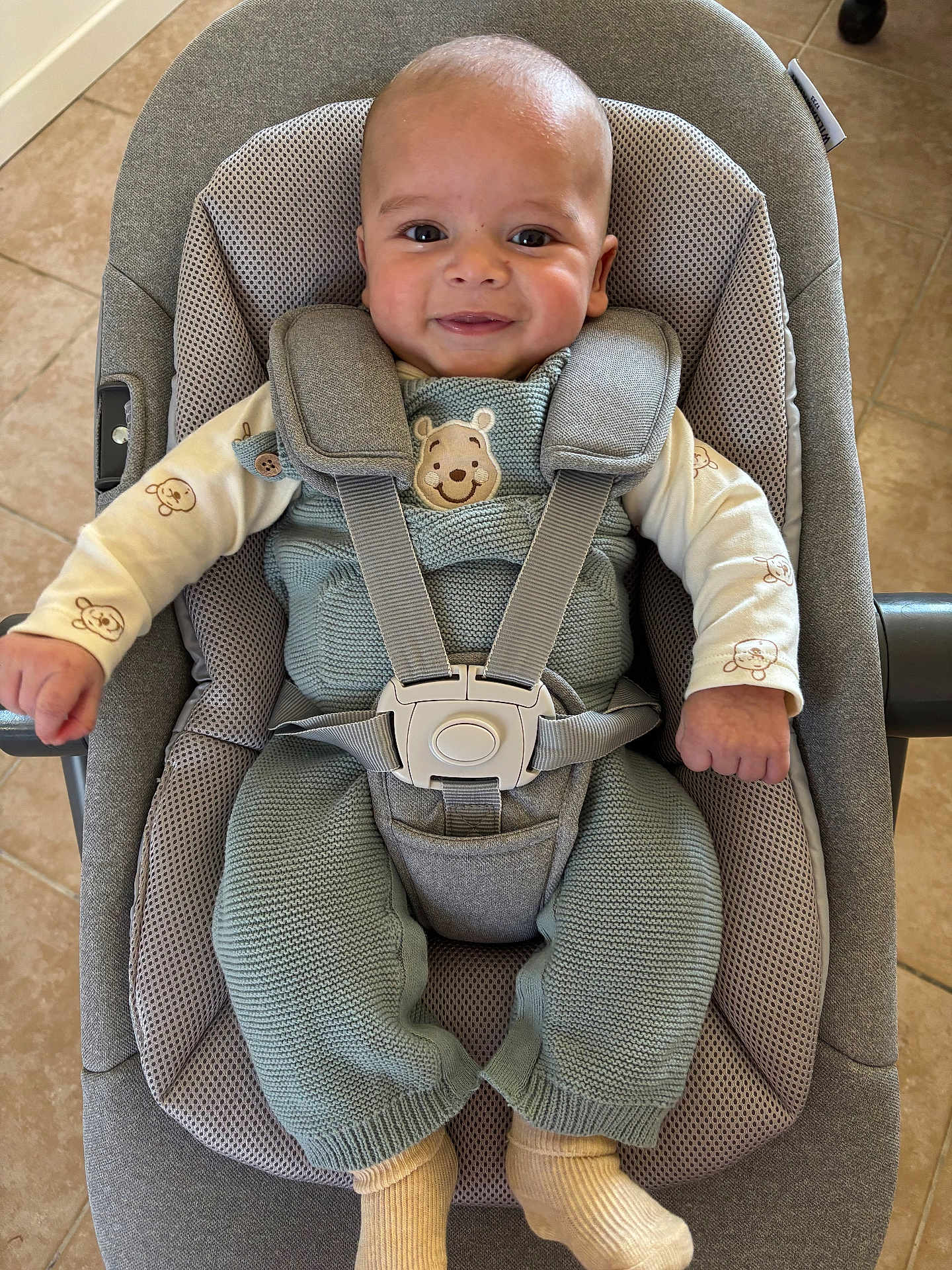 Sofiane participe au concours pour gagner de l'argent avec cette photo : baby, smiling, infant, knitted_clothing, baby_seat, safety_harness, face, head, hands, socks, floor, tile, cute, indoors, child, person, happy, seated, cozy, comfortable