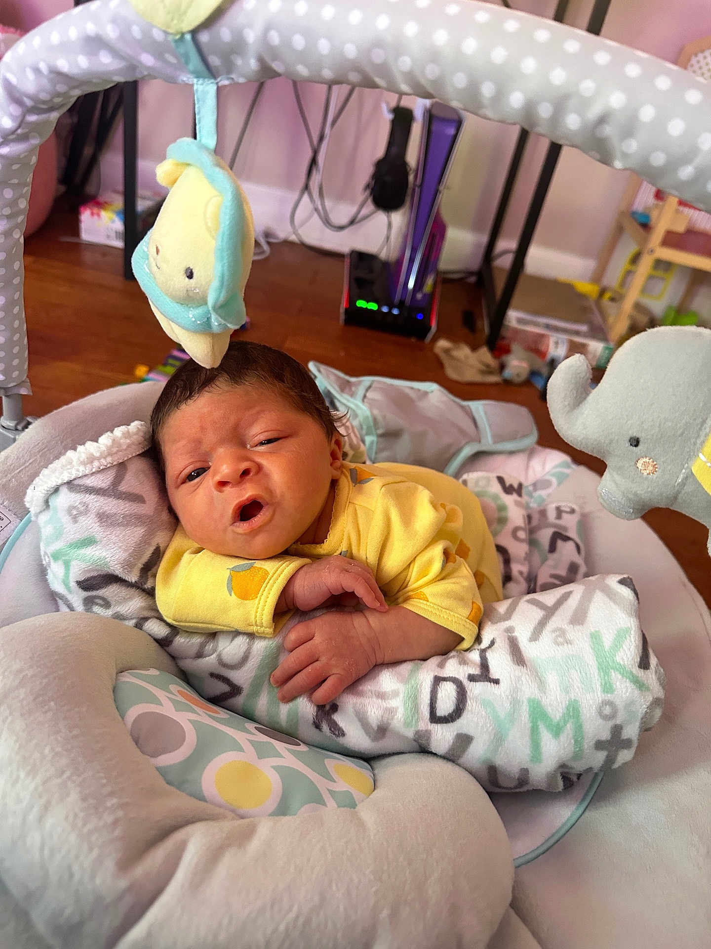 Kaida is registered to the contest to win money with this photo: baby, infant, blanket, plush_toy, yellow_clothing, cushion, face, hand, wooden_floor, baby_seat, indoor, soft_toys, expression, newborn, cute, resting, home, person, child, cozy