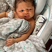 Kaida is registered to the contest to win money with this photo: baby, infant, blanket, heart_pattern, curly_hair, cushion, fabric, hand, indoors, newborn, person, portrait, seat, soft_texture, toddler, wrapped, young_child, face, expression, cozy