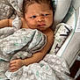 baby, infant, blanket, heart_pattern, curly_hair, cushion, fabric, hand, indoors, newborn, person, portrait, seat, soft_texture, toddler, wrapped, young_child, face, expression, cozy