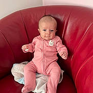 Louise participe au concours pour gagner de l'argent avec cette photo : baby, infant, pink_onesie, red_chair, towel, seated, indoor, cute, small_hands, small_feet, curious_expression, soft_lighting, head, face, person, child, furniture, comfortable, portrait, casual