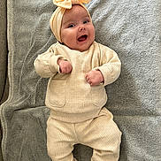 Myra a rejoint le concours — aidez-le/la à gagner de superbes lots ! baby, infant, smile, headband, beige_clothing, knitwear, blanket, soft_texture, happy, cute, lying_down, small_hands, white_socks, indoors, portrait, child, cozy, warm, content, person