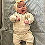 baby, infant, smile, headband, beige_clothing, knitwear, blanket, soft_texture, happy, cute, lying_down, small_hands, white_socks, indoors, portrait, child, cozy, warm, content, person
