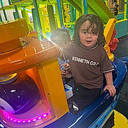 Ishamel Orta is registered to the contest to win money with this photo: amusement, arcade, blue, child, colorful, curly_hair, entertainment, family_fun, indoor, neon_lights, orange, passenger, play_center, playground, ride, seated, smiling, toddler, vehicle, yellow