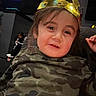 adult, background, camouflage, casual, chair, child, close_up, crown, eyes, face, gold_crown, indoor, living_room, photograph, portrait, royalty, seated, shirt, smile, toddler