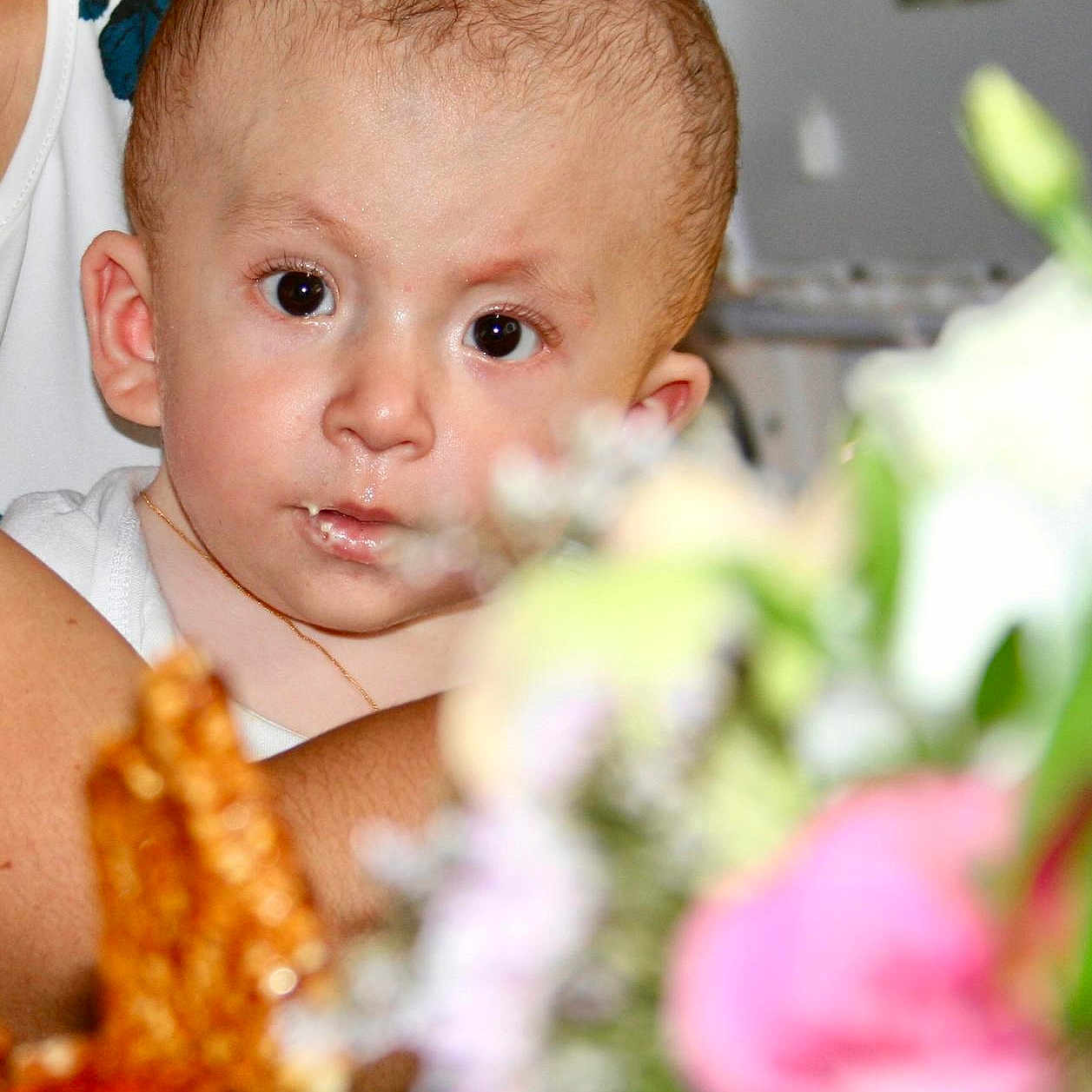 Marie participe au concours pour gagner de l'argent avec cette photo : adult, arm, baby, blurred_background, child, closeup, curious, expression, eyes, face, flower, hair, head, holding, indoor, necklace, person, portrait, skin, white_clothing