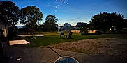Cyrus is registered to the contest to win money with this photo: baby, bottle, earmuffs, fireworks, night, outdoor, backyard, grass, trees, chair, person, infant, darkness, light, celebration, quiet, peaceful, relaxation, seat, evening