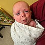 Cyrus is registered to the contest to win money with this photo: baby, blanket, face, person, infant, expression, pout, wrapped, maroon_clothing, indoor, toy_board, floor, holding, cute, child, skin, head, blue_eyes, portrait, young