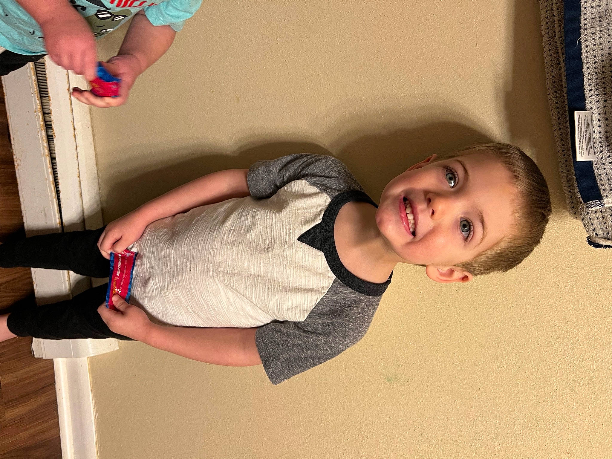 Carson is registered to the contest to win money with this photo: child, clothing, elbow, finger, fun, hand, happy, human_body, human_leg, joint, joy, knee, leg, organ, person, smile, sock, textile, thigh, toddler