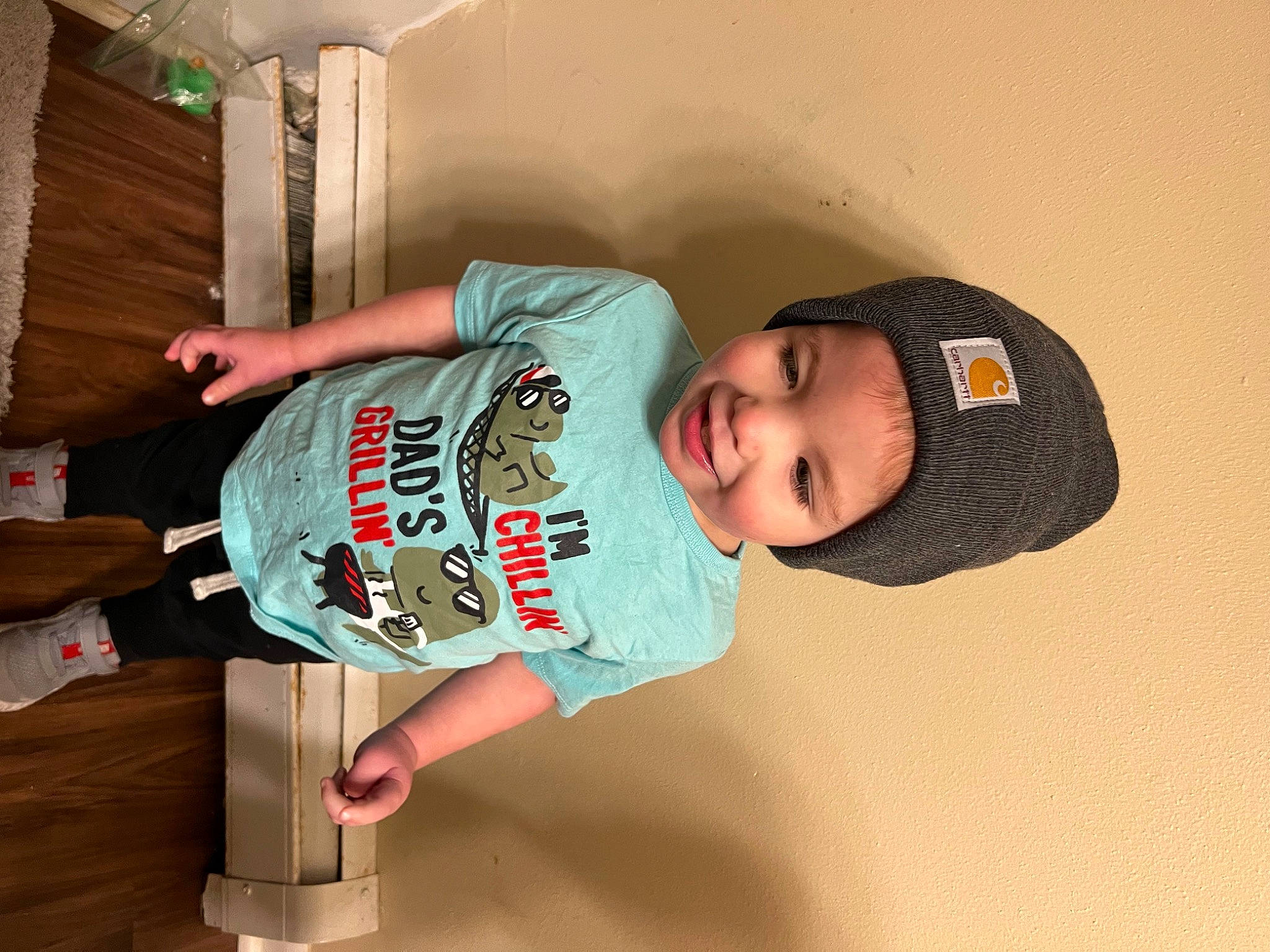 Oliver is registered to the contest to win money with this photo: arm, baby, baby_toddler_clothing, baseball_cap, child, elbow, fun, happy, hat, headwear, joint, joy, knee, person, room, shoulder, sleeve, smile, standing, t_shirt