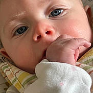 Abrie joined the competition — help win amazing prizes! baby, close_up, blue_eyes, hand, blanket, striped_blanket, white_outfit, pink_stars, skin, face, infant, cute, soft_lighting, portrait, young_child, sucking_hand, cozy, newborn, expression, indoors