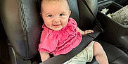 Aniyah joined the competition — help win amazing prizes! baby, child, car_seat, seatbelt, smiling, pink_clothing, white_shorts, leather_seat, infant, person, sitting, happy, interior, vehicle, cute, small_child, safety, car, seat, casual