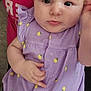 baby, infant, purple_dress, headband, lemon_print, cute, serious_face, hand, person_holding, red_shirt, closeup, portrait, indoors, young_child, child, skin, clothing, expression, human, sitting