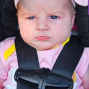Aniyah is registered to the contest to win money with this photo: baby, infant, car_seat, headband, pink_clothing, straps, serious_expression, child, closeup, portrait, seatbelt, safety, cute, face, person, young_child, indoors, human, fashion, accessory