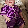 baby, child, pajamas, purple_clothing, smiling, couch, blanket, indoor, infant, happy, face, portrait, sitting, soft_fabric, buttoned_shirt, short_sleeves, legs, head, skin, cozy
