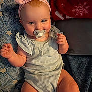 Joy is registered to the contest to win money with this photo: baby, pacifier, headband, blanket, star_pattern, red_blanket, infant, smile, cute, chubby_cheeks, clothing, sitting, person, skin, hand, legs, face, indoors, portrait, soft_texture
