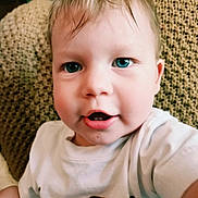 Beckham is registered to the contest to win money with this photo: baby, background, blue_eyes, child, close_up, curly_hair, cute, expression, face, head, indoor, mouth, person, portrait, sitting, skin, smiling, texture, white_shirt, young