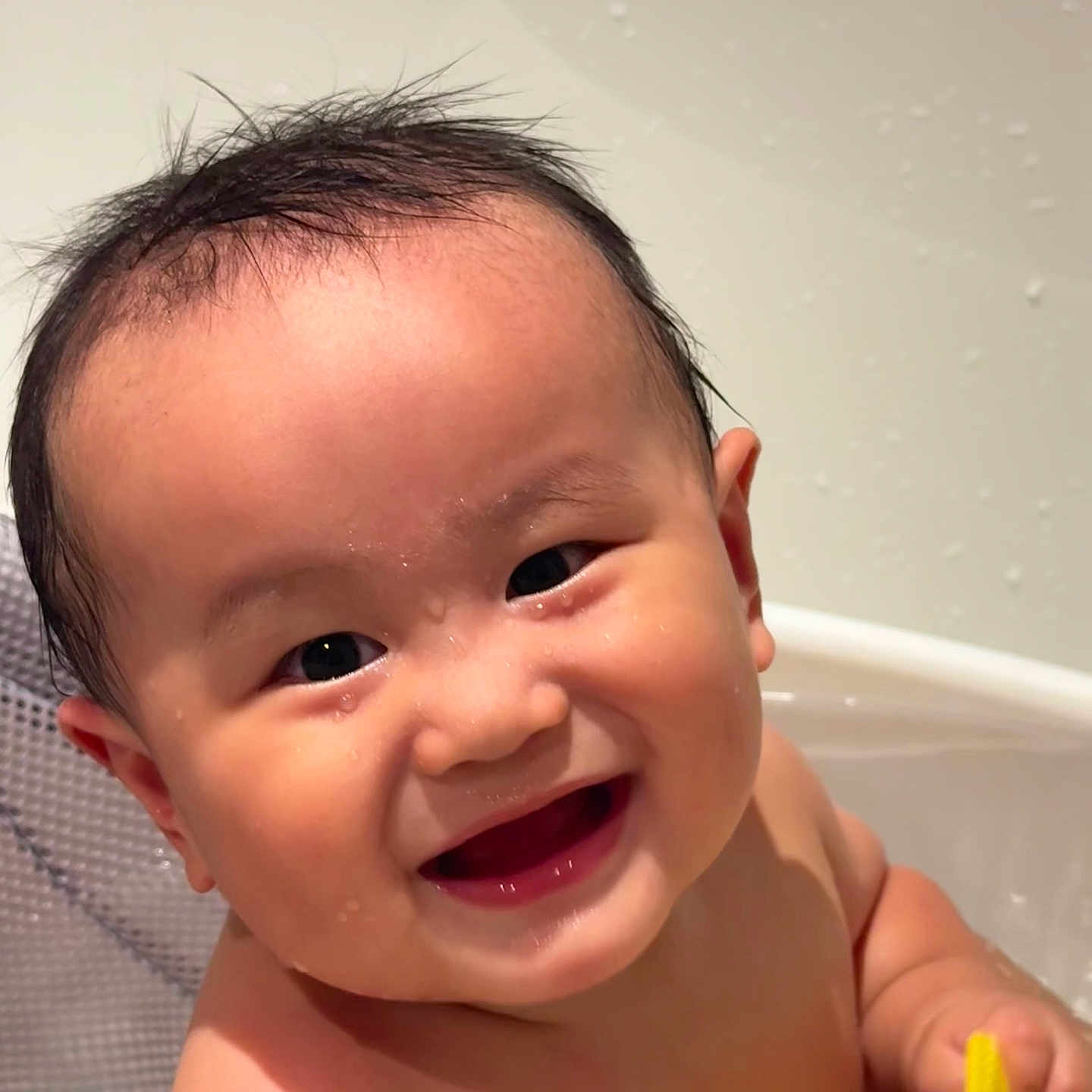 Lucas is registered to the contest to win money with this photo: baby, smile, bathtub, water, wet_hair, toy, child, happy, face, skin, hand, play, bath_time, cute, indoors, infant, person, expression, closeup, joy