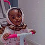 Aissata participe au concours pour gagner de l'argent avec cette photo : toddler, child, indoor, tricycle, pink, scarf, hoodie, clothing, toy, face, person, grip, floor, wall, expression, small_child, transportation, handlebars, curious, cozy