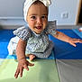 baby, child, girl, smiling, reaching, headband, bow, dress, patterned_clothing, play_mat, indoor, happy, cute, portrait, closeup, person, skin, arm, foot, floor