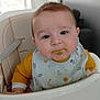 baby, bib, child, curious, cute, expression, face, feeding_time, food, furniture, high_chair, home, indoor, infant, messy_face, portrait, space_pattern, toddler, yellow_clothing, young_child