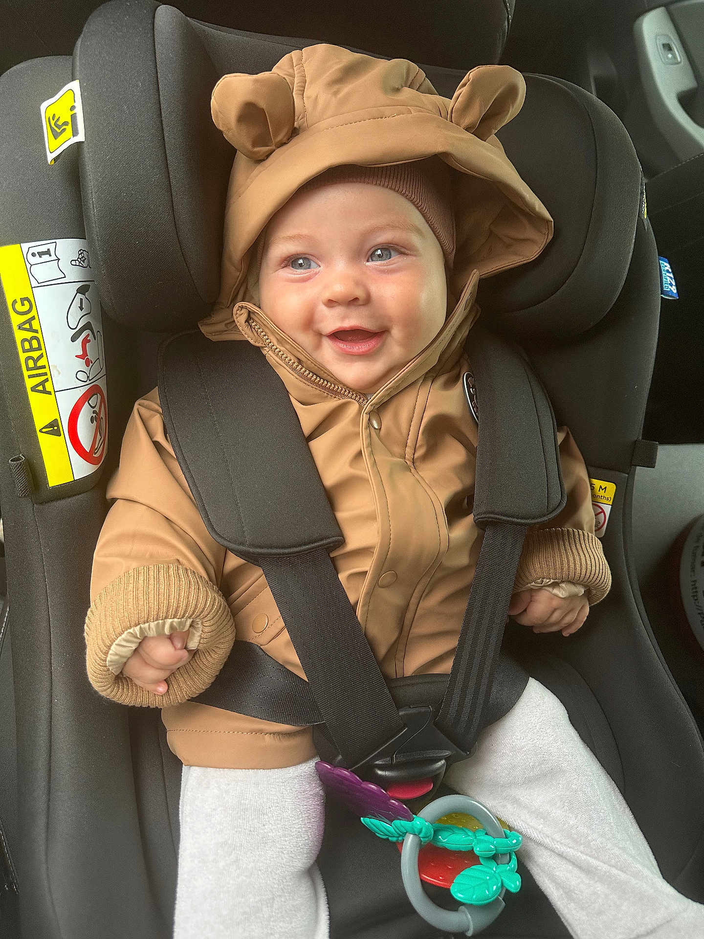 Isaël participe au concours pour gagner de l'argent avec cette photo : baby, bear_ears, car_interior, car_seat, child, clothing, cozy, cute, face, hands, happy, hood, infant, jacket, safety, seatbelt, smile, toy, transportation, warm