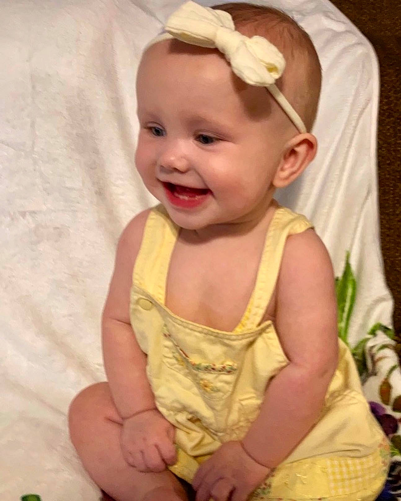 Olive is registered to the contest to win money with this photo: baby, baby_products, baby_toddler_clothing, cheek, child, eye, finger, happy, head, headband, headgear, iris, joy, lip, pattern, person, pink, skin, sleeve, smile