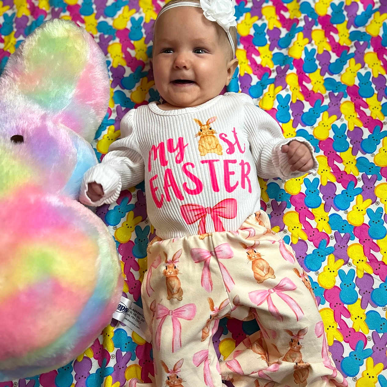 Amelia joined the competition — help win amazing prizes! baby, balloon, clothing, costume, dress, face, happy, hat, head, homedecor, pajamas, pants, people, person, photography, portrait, purple, quilt, sitting, toy