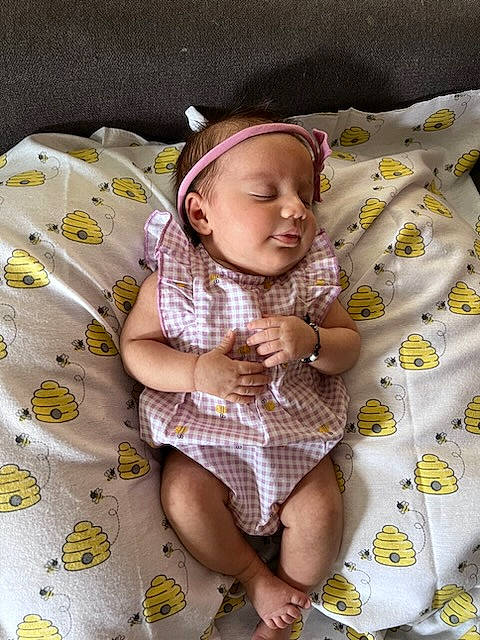 Ethel is registered to the contest to win money with this photo: baby, baby_products, baby_toddler_clothing, bed_sheet, bedding, child, comfort, flooring, foot, happy, linens, pattern, person, purple, room, sitting, skin, sleeve, sock, textile